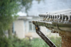 Close-up of rainwater pouring from the gutter illustrating basement leak prevention in Maryland. 