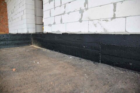 Worker Applying Waterproofing Treatment to a Basement Wall in Maryland