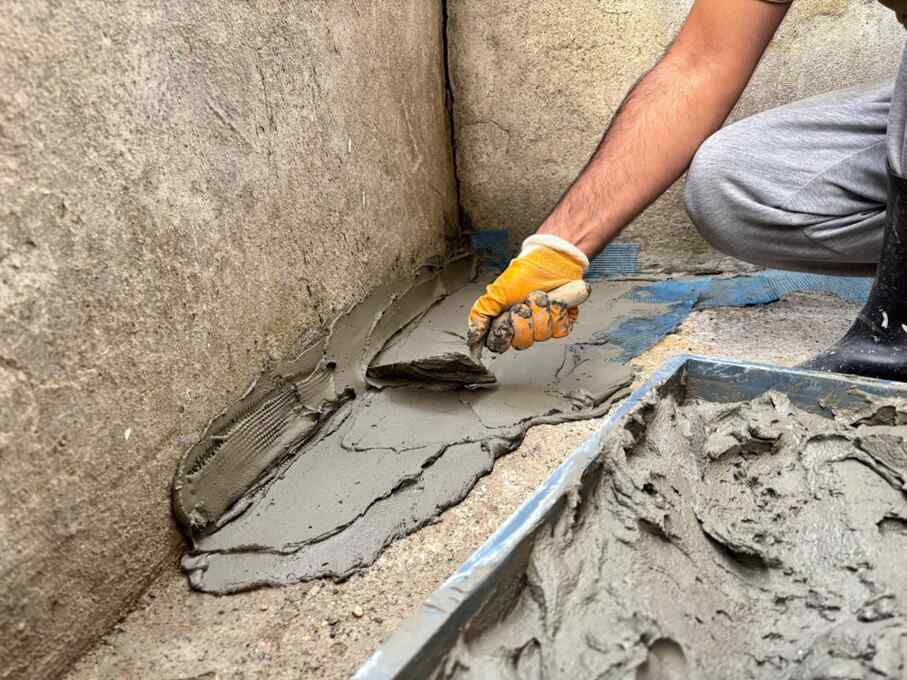 A professional applying waterproofing cement at a residential house in Maryland