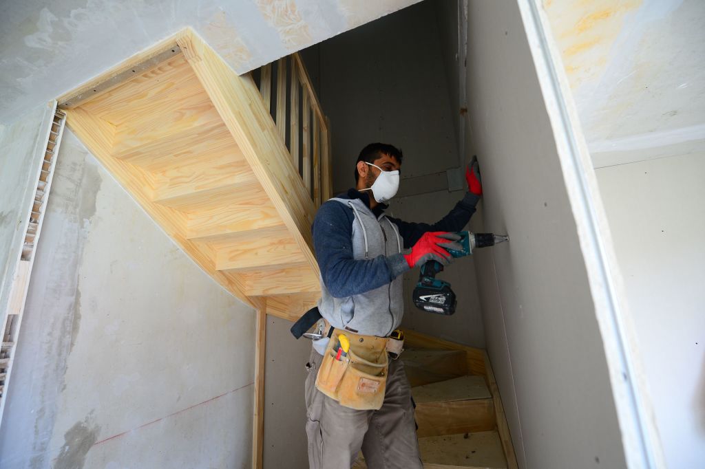 Construction worker driving a drywall screw into a wall