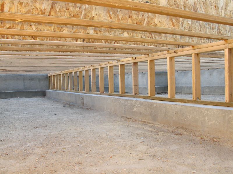 Crawl space with wooden floor joists and support framing beneath a residential home
